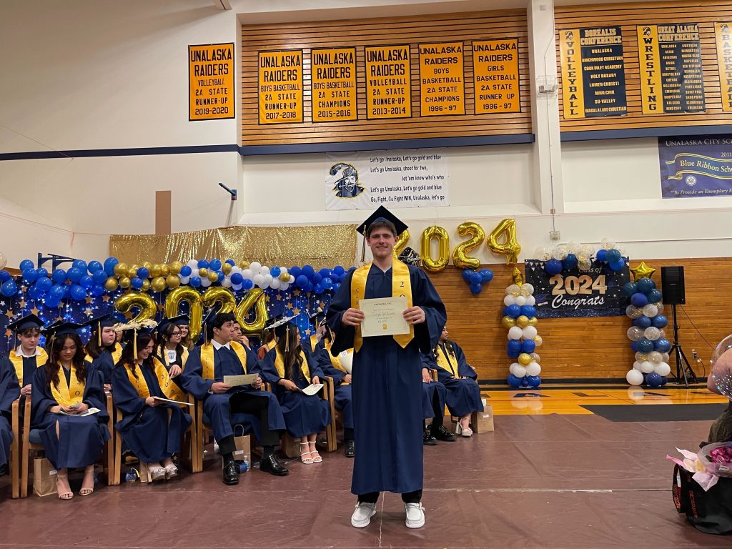 Gage Williams holding his scholarship during graduation